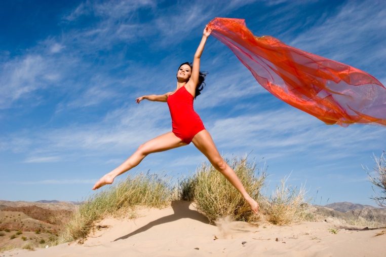 Eine Frau springt an einem Sandstrand in die Luft